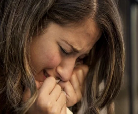 Woman crying and holding hands to face in distress
